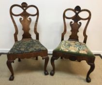 Two very similar George I walnut dining chairs with shell carved and bow decorated top rail over a