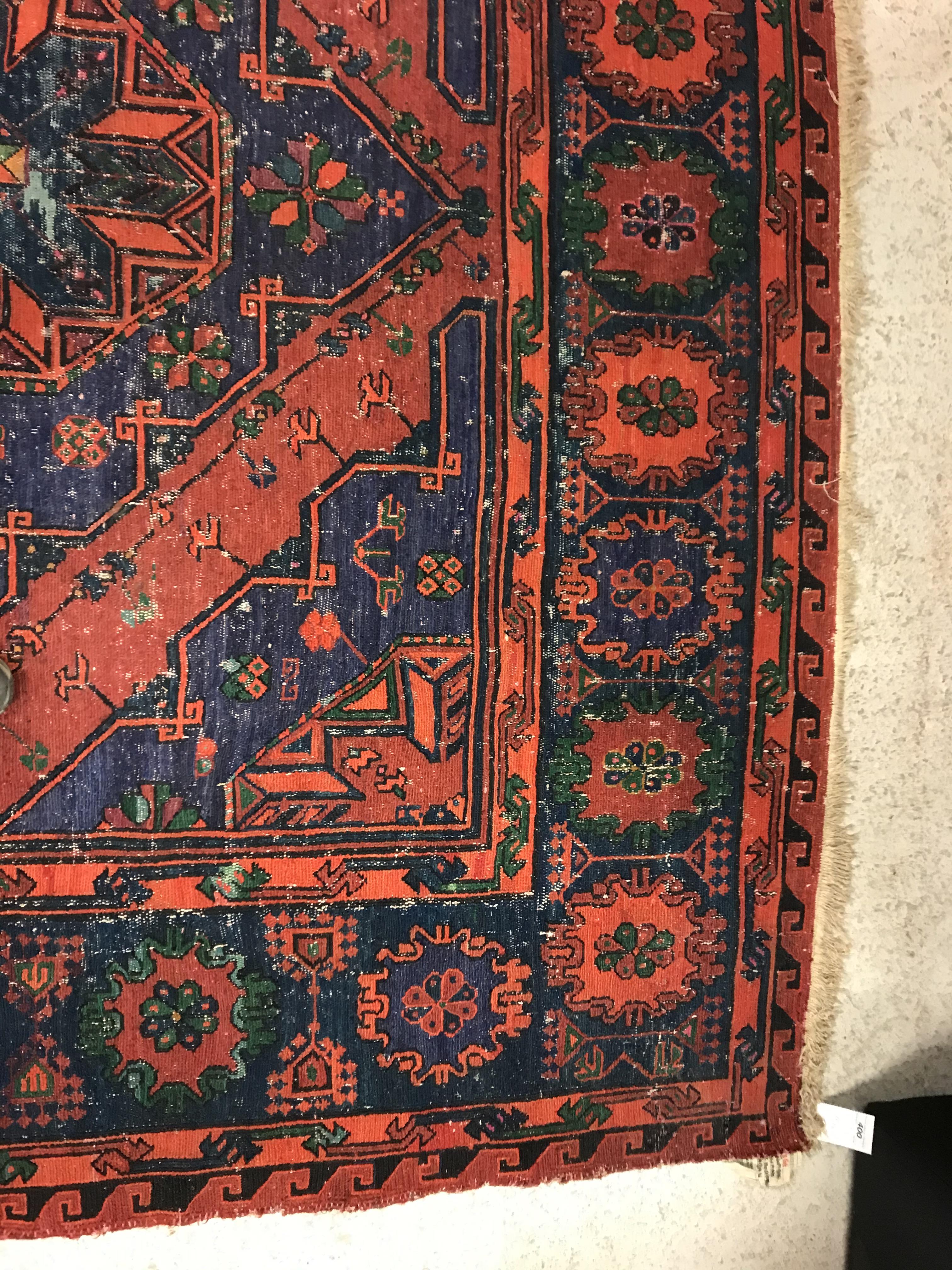 A Persian rug with three repeating lozenge medallions on a red and blue ground, within a blue, red - Image 9 of 20