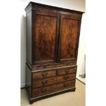 A late George III mahogany linen press, the moulded cornice over two oval figured panelled doors,