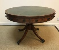 A Regency mahogany drum table, the top with tooled and gilded leather insert over four real and four