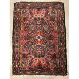 A Persian rug, the central panel set with stylised foliate decoration on a salmon pink ground within