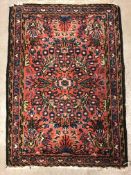 A Persian rug, the central panel set with stylised foliate decoration on a salmon pink ground within