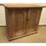 A Victorian pine two door cupboard, the domed panelled doors enclosing two shelves on a plinth base,