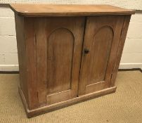 A Victorian pine two door cupboard, the domed panelled doors enclosing two shelves on a plinth base,