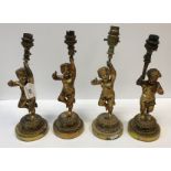 Three gilt brass table lights as putti holding aloft a torch, now as an electric light fitting,