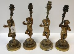 Three gilt brass table lights as putti holding aloft a torch, now as an electric light fitting,