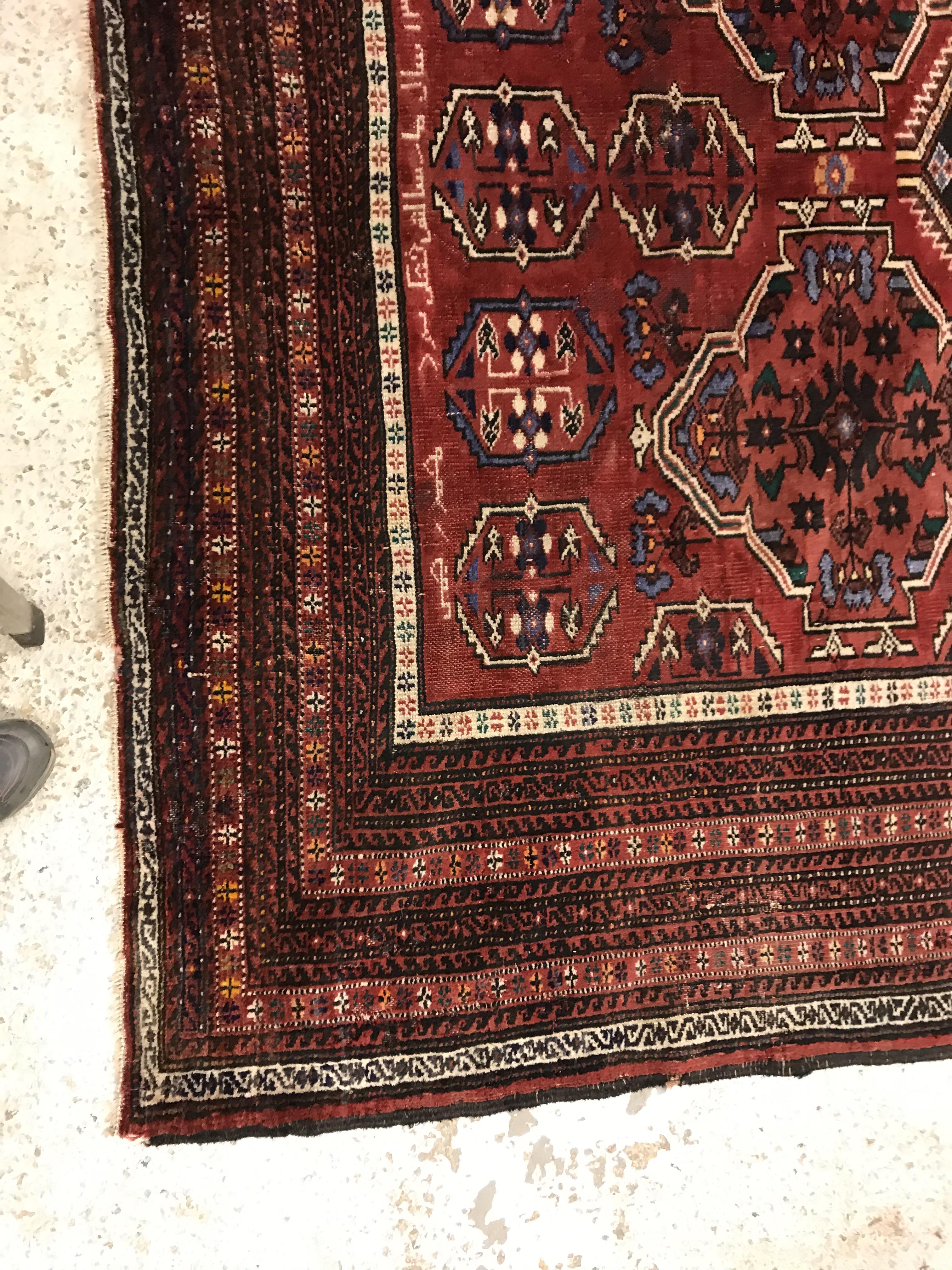 A Caucasian carpet, the central panel set with repeating medallion decoration on a blood red - Image 2 of 15