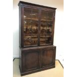 An early 19th Century mahogany bookcase cabinet, the moulded cornice above two glazed and barred