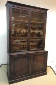 An early 19th Century mahogany bookcase cabinet, the moulded cornice above two glazed and barred