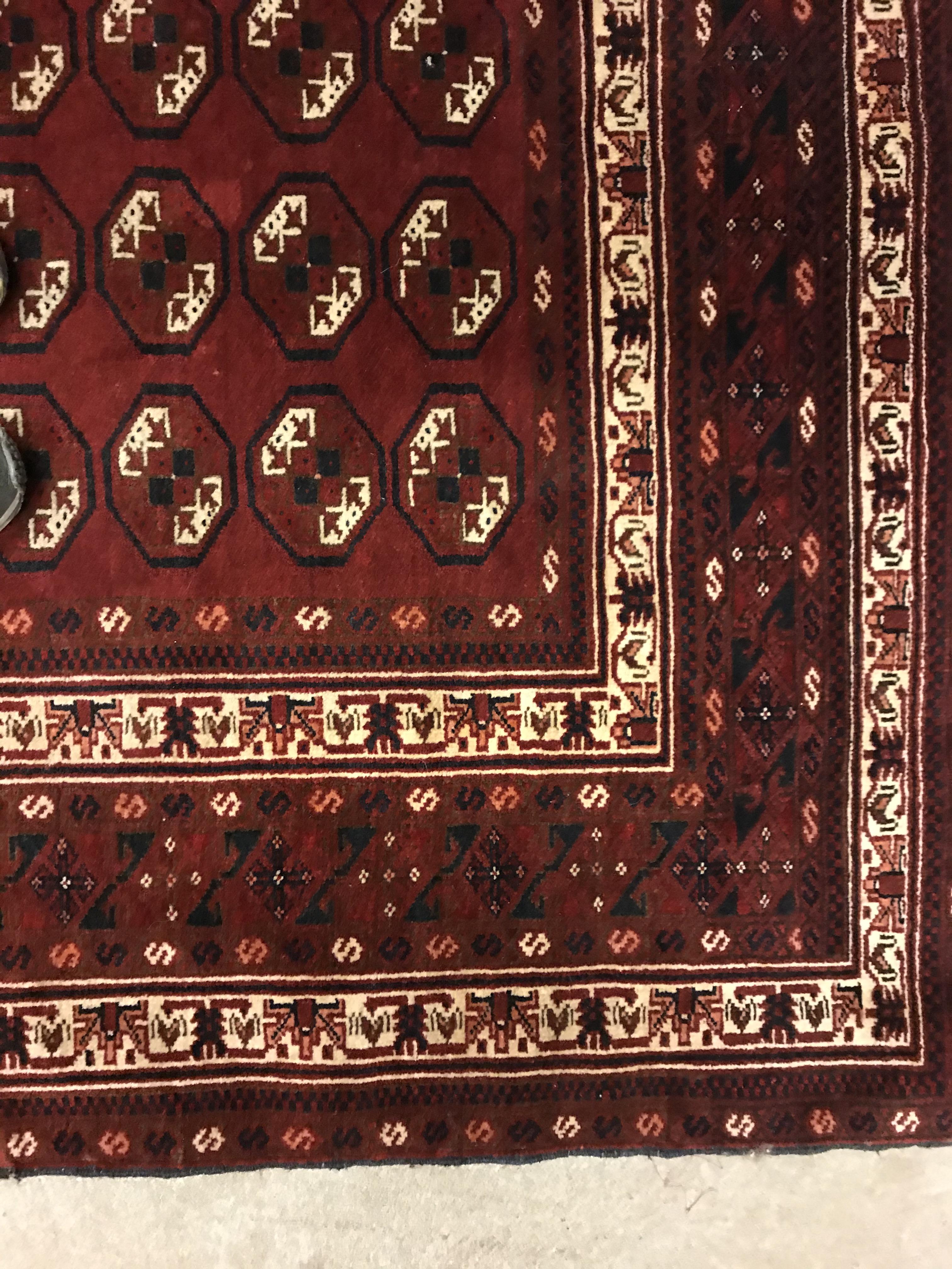 A Bokhara rug, the central panel set with repeating elephant foot style medallions on a dark red - Image 8 of 12