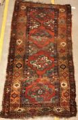 A Caucasian rug, the central panel set with repeating medallions on a red ground, within a stepped