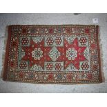 A Caucasian rug, the central panel set with two star shaped medallions on a mint green ground,