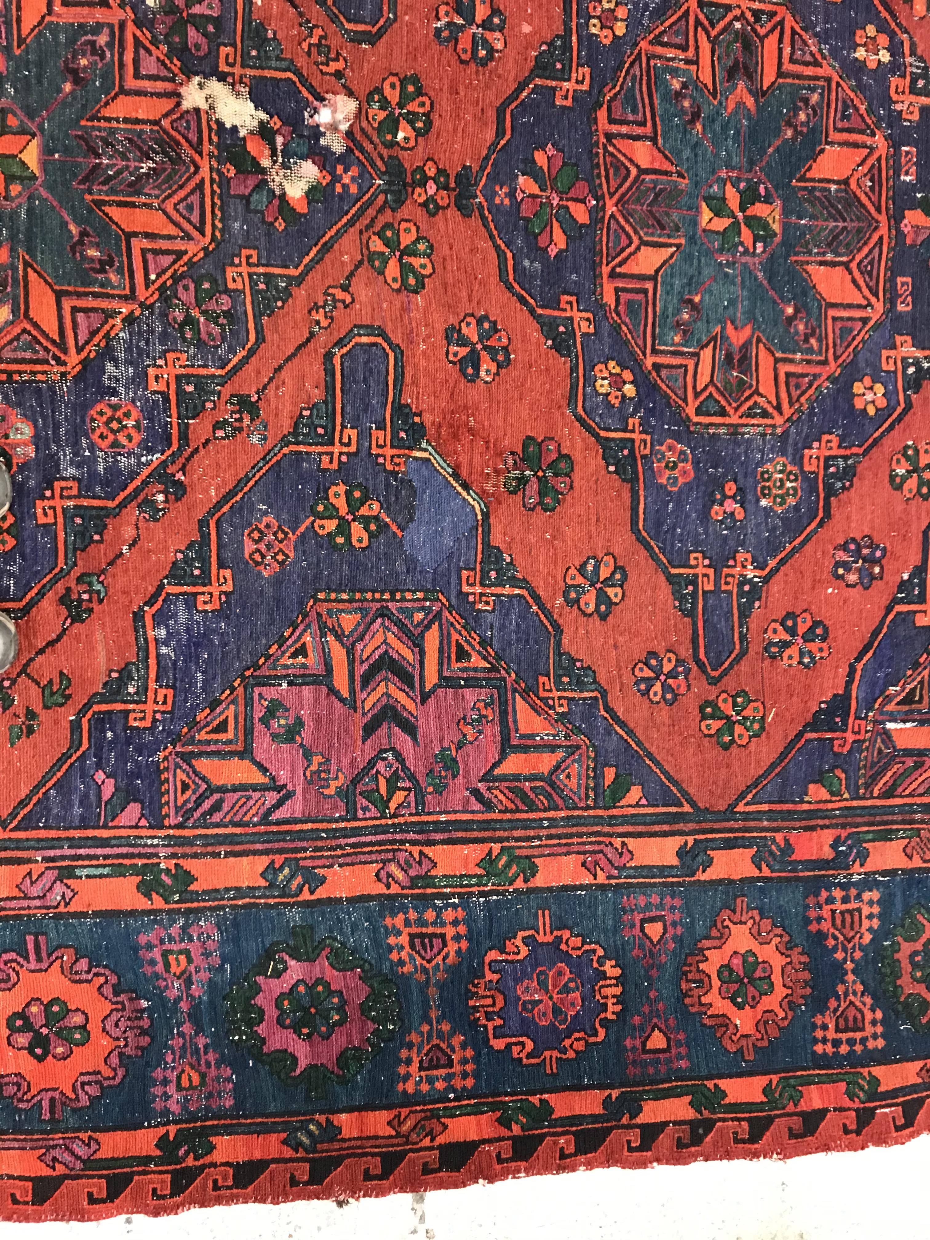 A Persian rug with three repeating lozenge medallions on a red and blue ground, within a blue, red - Image 5 of 20