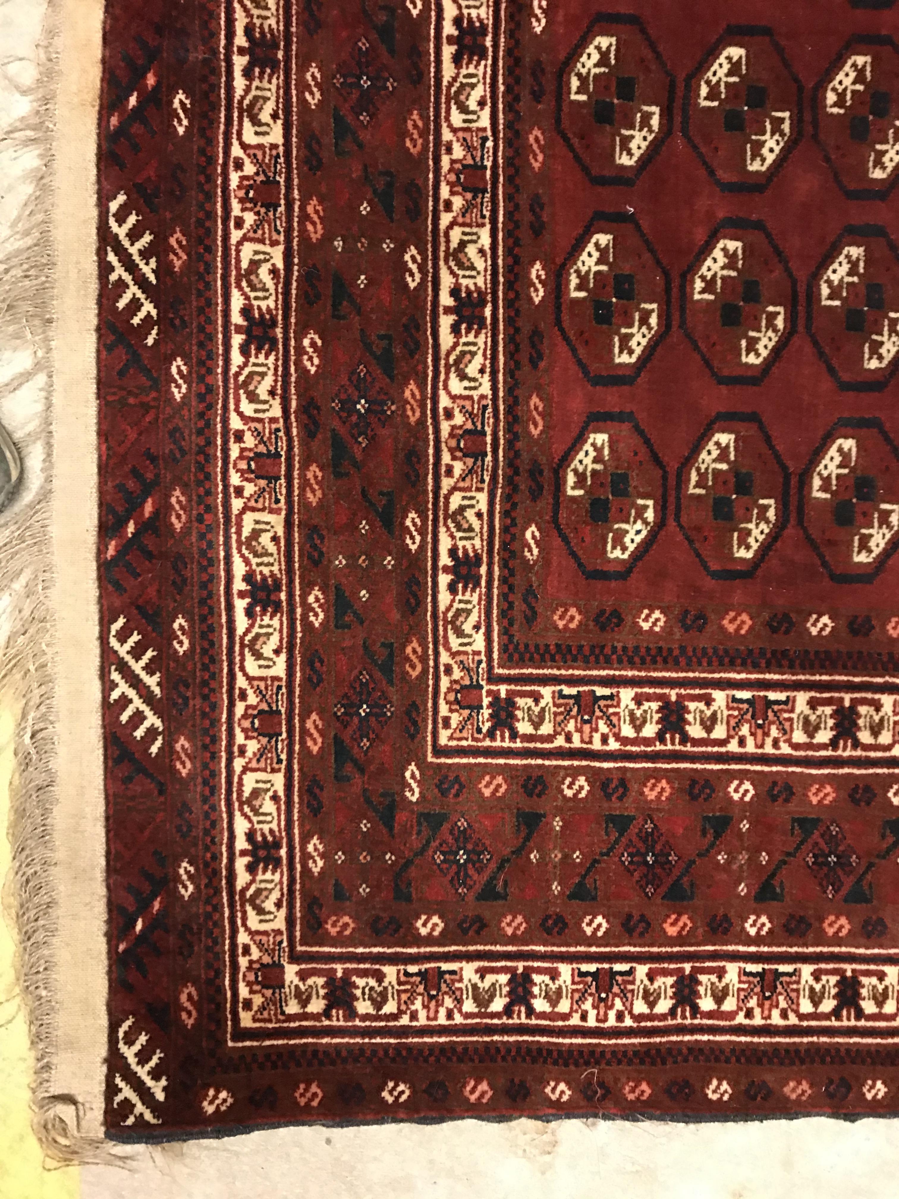 A Bokhara rug, the central panel set with repeating elephant foot style medallions on a dark red - Image 3 of 12