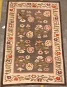 A Kelim rug, the central panel set with floral sprays on a mushroom ground, within a stepped border,