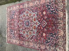 A Caucasian carpet, the central panel set with a flower head medallion on a red ground, with all