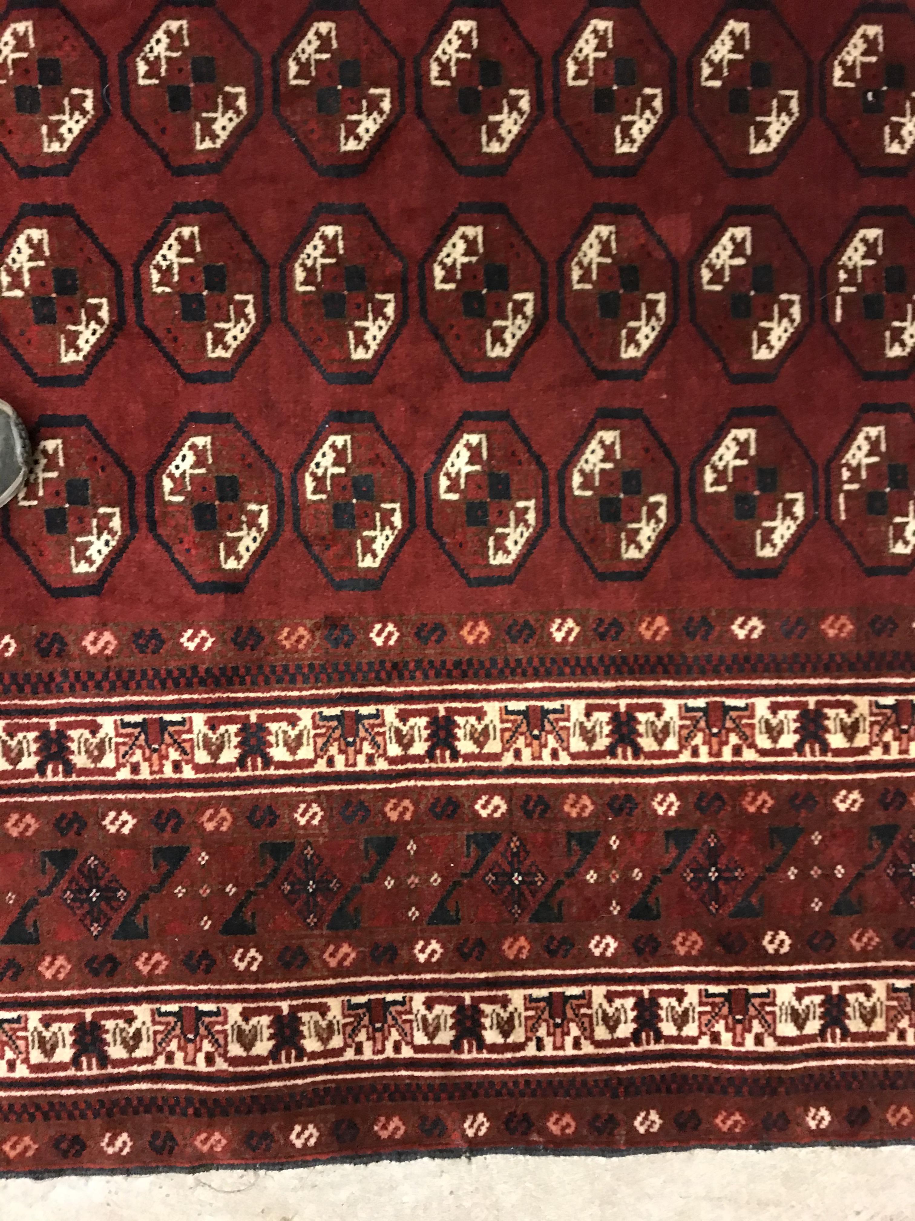 A Bokhara rug, the central panel set with repeating elephant foot style medallions on a dark red - Image 7 of 12