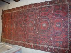 A Beshir carpet, the central panel set with repeating stylised floral motifs in red and black,