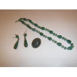 A modern jade bead necklace, 47.5 cm long, a brass mounted cabochon cut oval jade brooch, 3.3 cm x