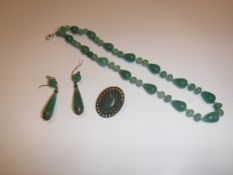 A modern jade bead necklace, 47.5 cm long, a brass mounted cabochon cut oval jade brooch, 3.3 cm x