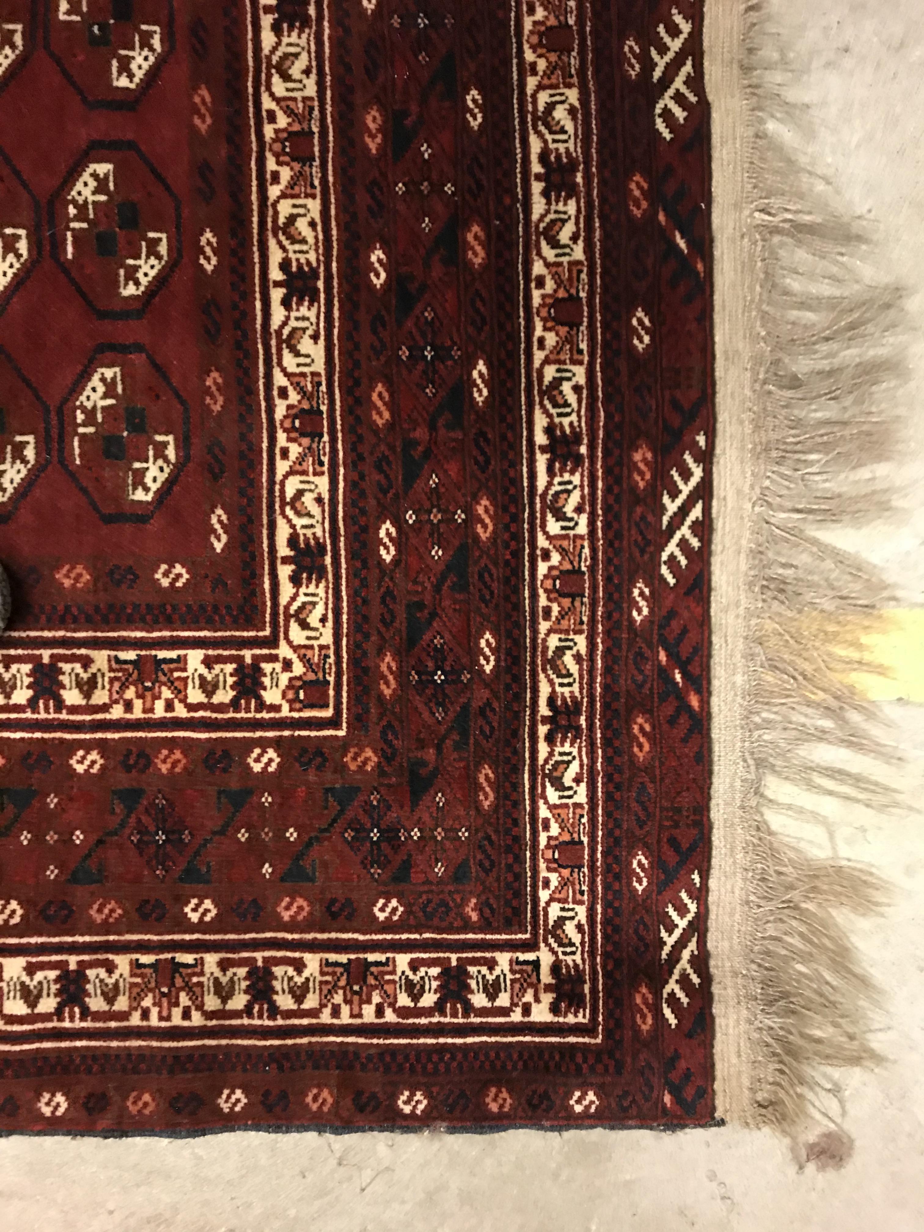 A Bokhara rug, the central panel set with repeating elephant foot style medallions on a dark red - Image 11 of 12