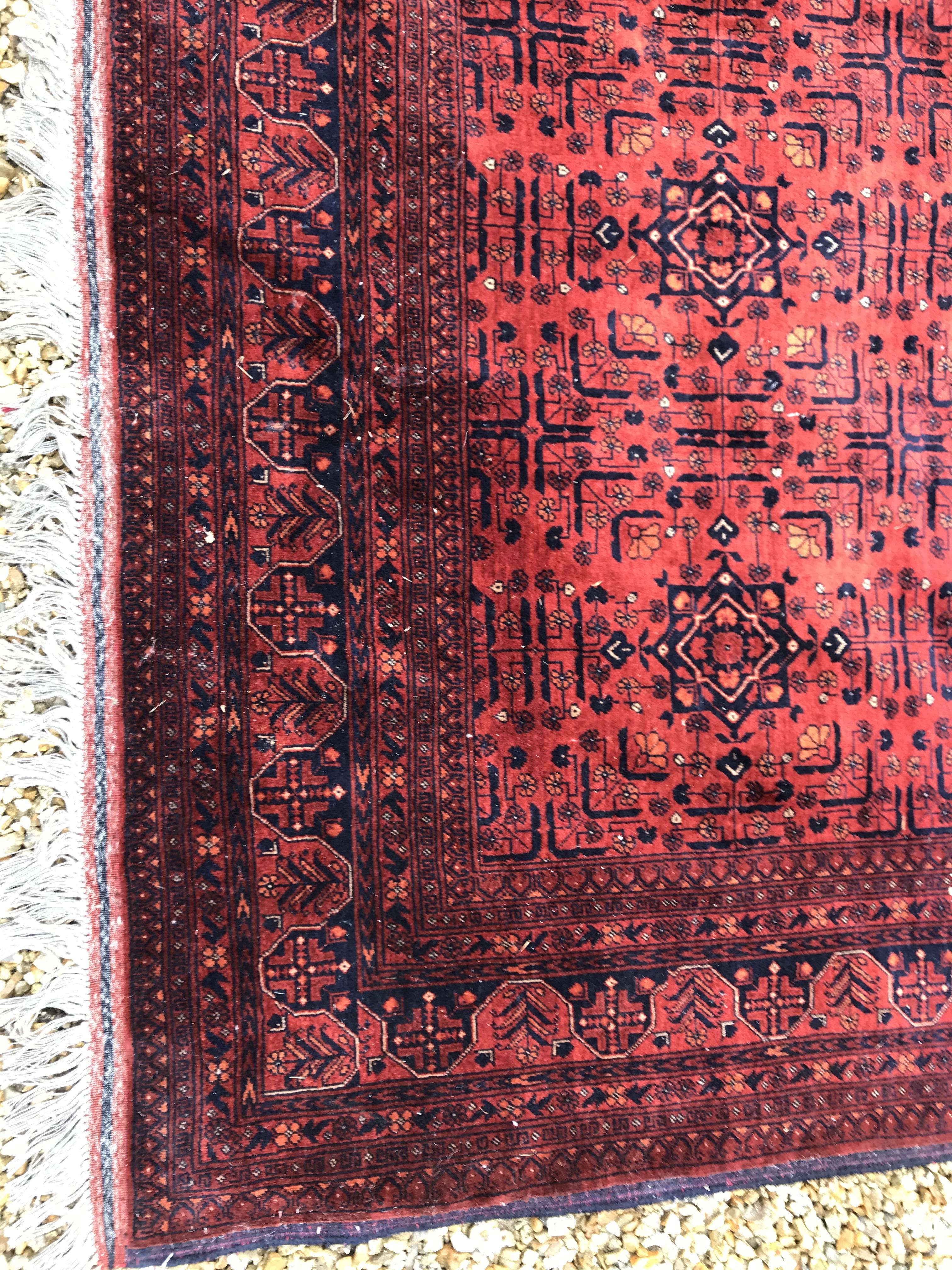 A Bokhara type carpet, the central panel set with repeating medallions on a dark red and black - Image 3 of 23