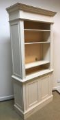 A modern cream painted bookcase cabinet in the Georgian style, the upper section with adjustable