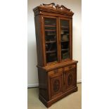 A Victorian walnut bookcase cabinet, the upper section with broken arch pediment over two glazed