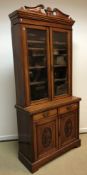A Victorian walnut bookcase cabinet, the upper section with broken arch pediment over two glazed