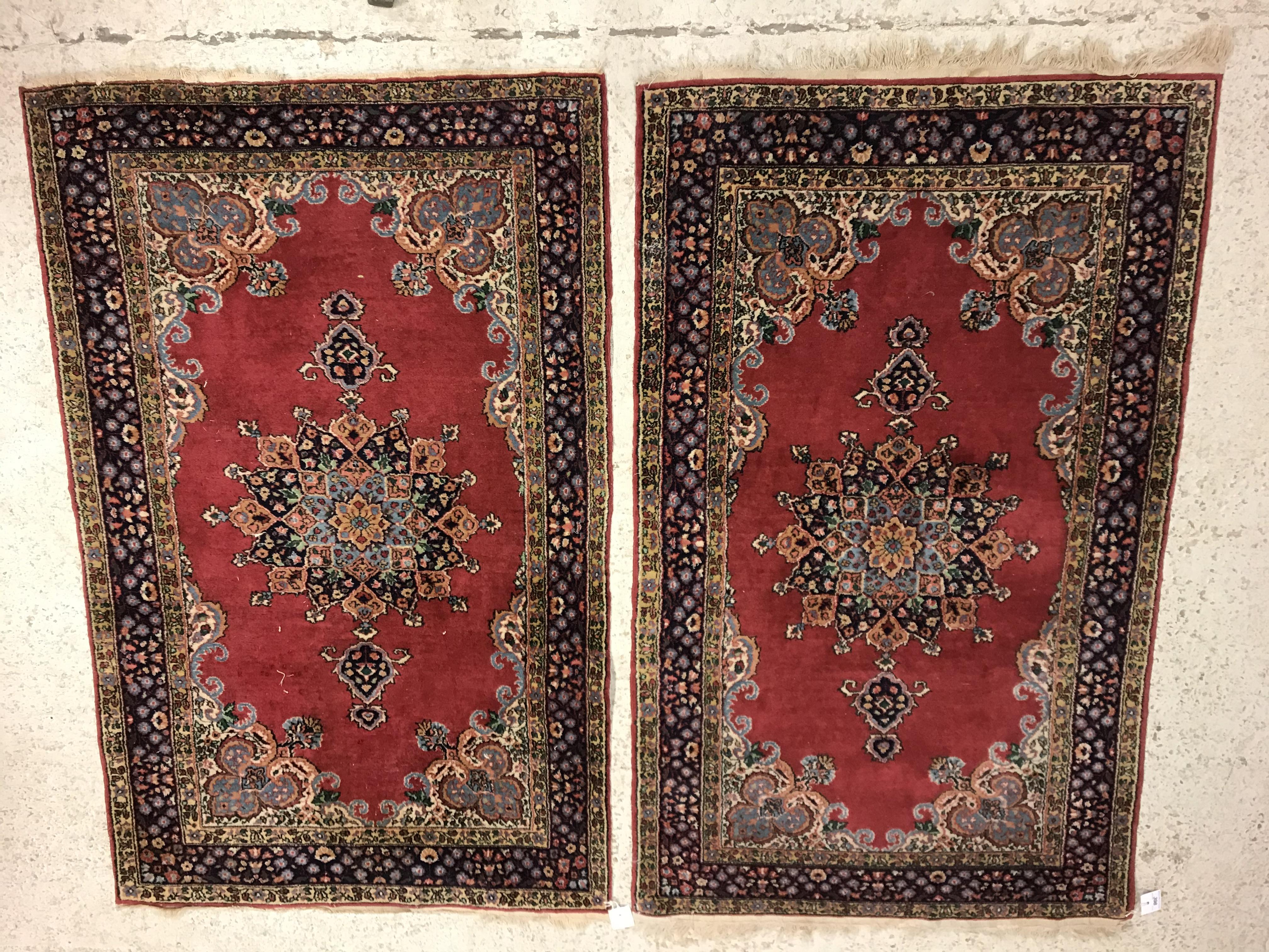 A pair of fine Oriental rugs, the central panels set with floral decorated circular medallion on a