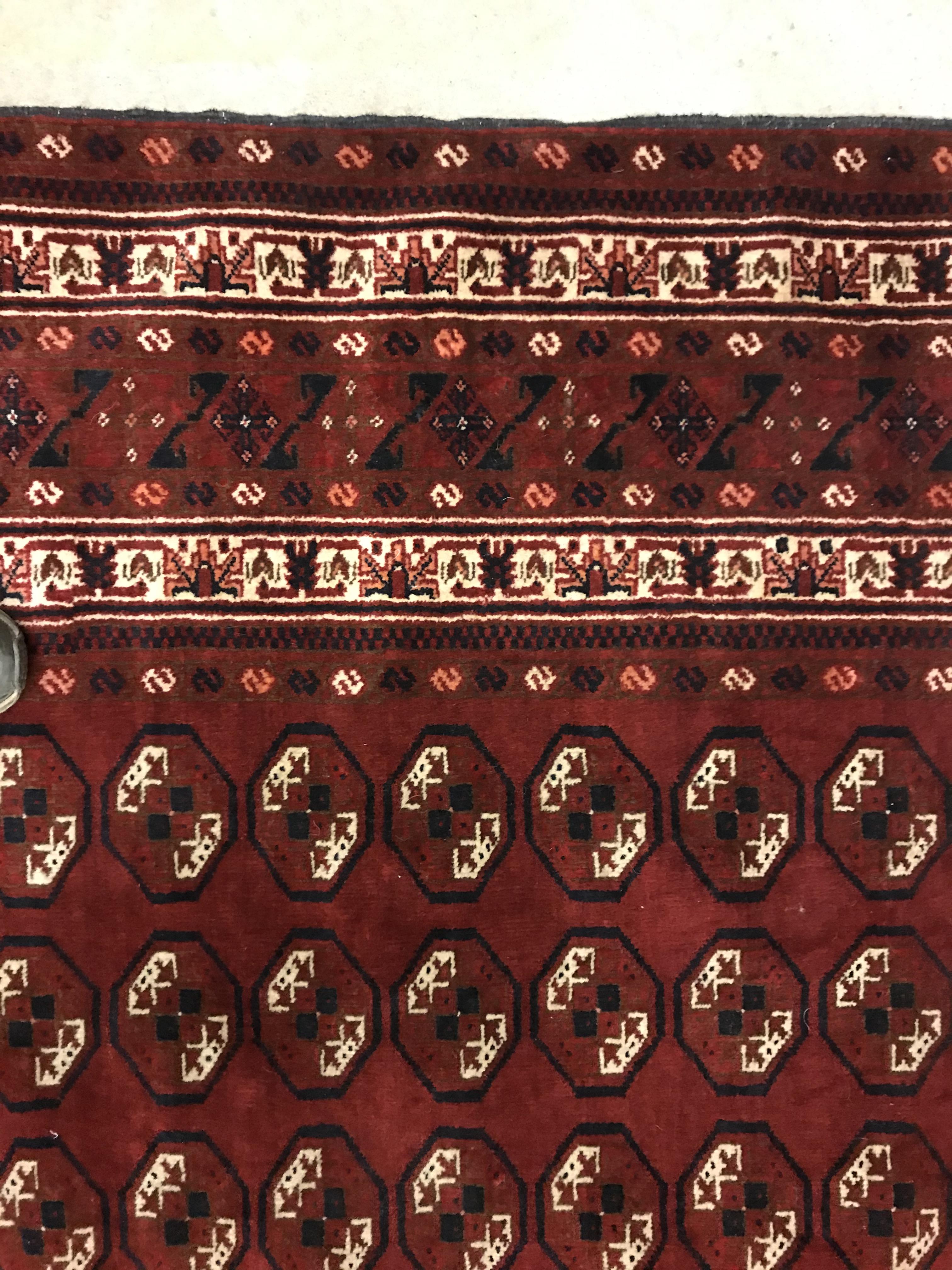 A Bokhara rug, the central panel set with repeating elephant foot style medallions on a dark red - Image 5 of 12