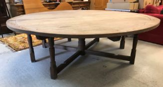 An Arts & Crafts style pine centre table, the cross-banded circular top on seven (of eight) turned