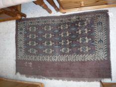 A Bokhara Juval rug, the main panel set with stylised elephant foot medallions on an aubergine