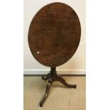 A 19th Century oak tea table, the circular snap top on a turned pedestal to hipped tripod base, 70