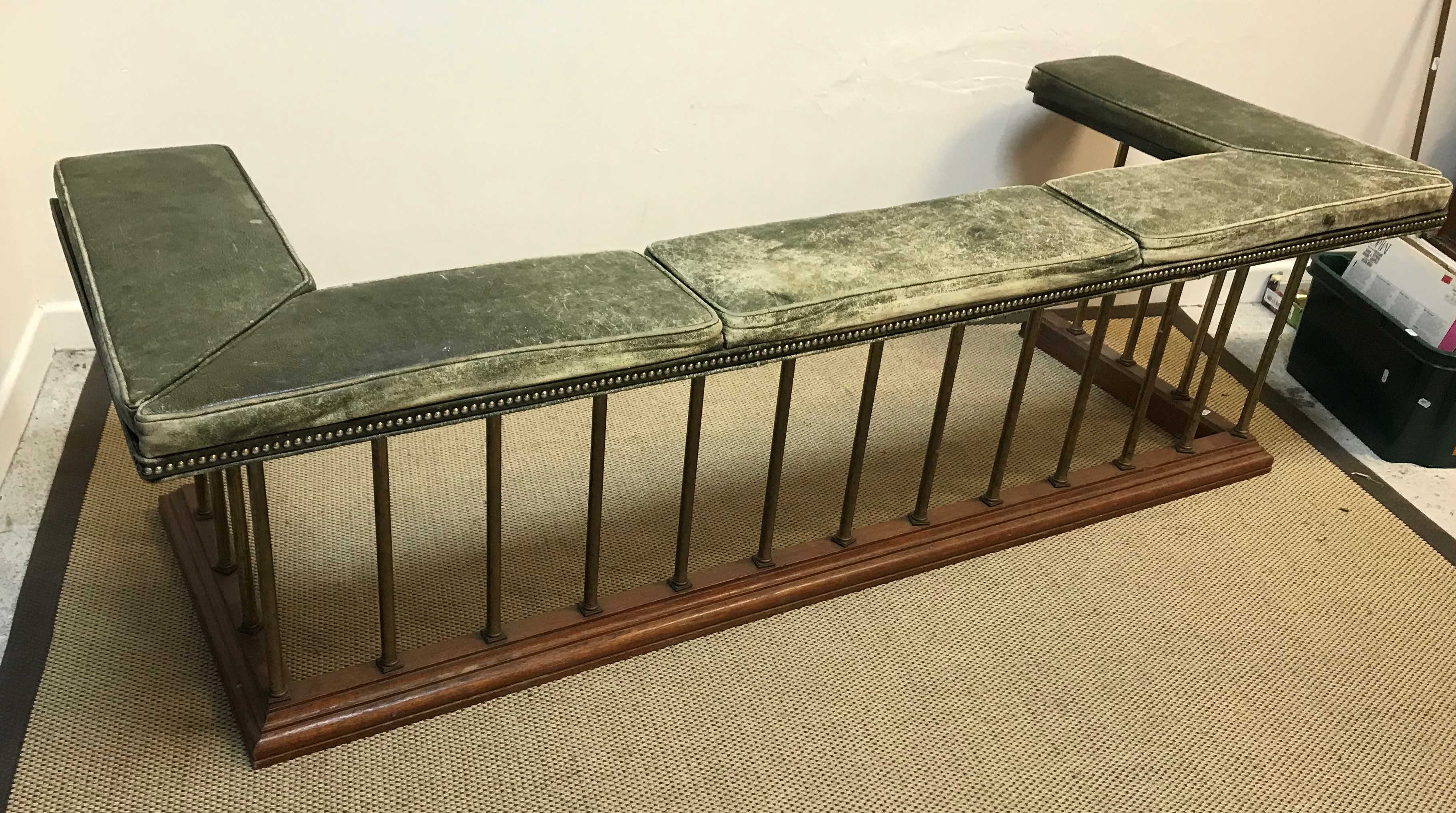 An early 20th Century green leather upholstered and brass railed club fender on an oak base with