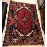 A Shiraz rug, the central panel set with lozenge shaped medallion on a red and cream ground within a