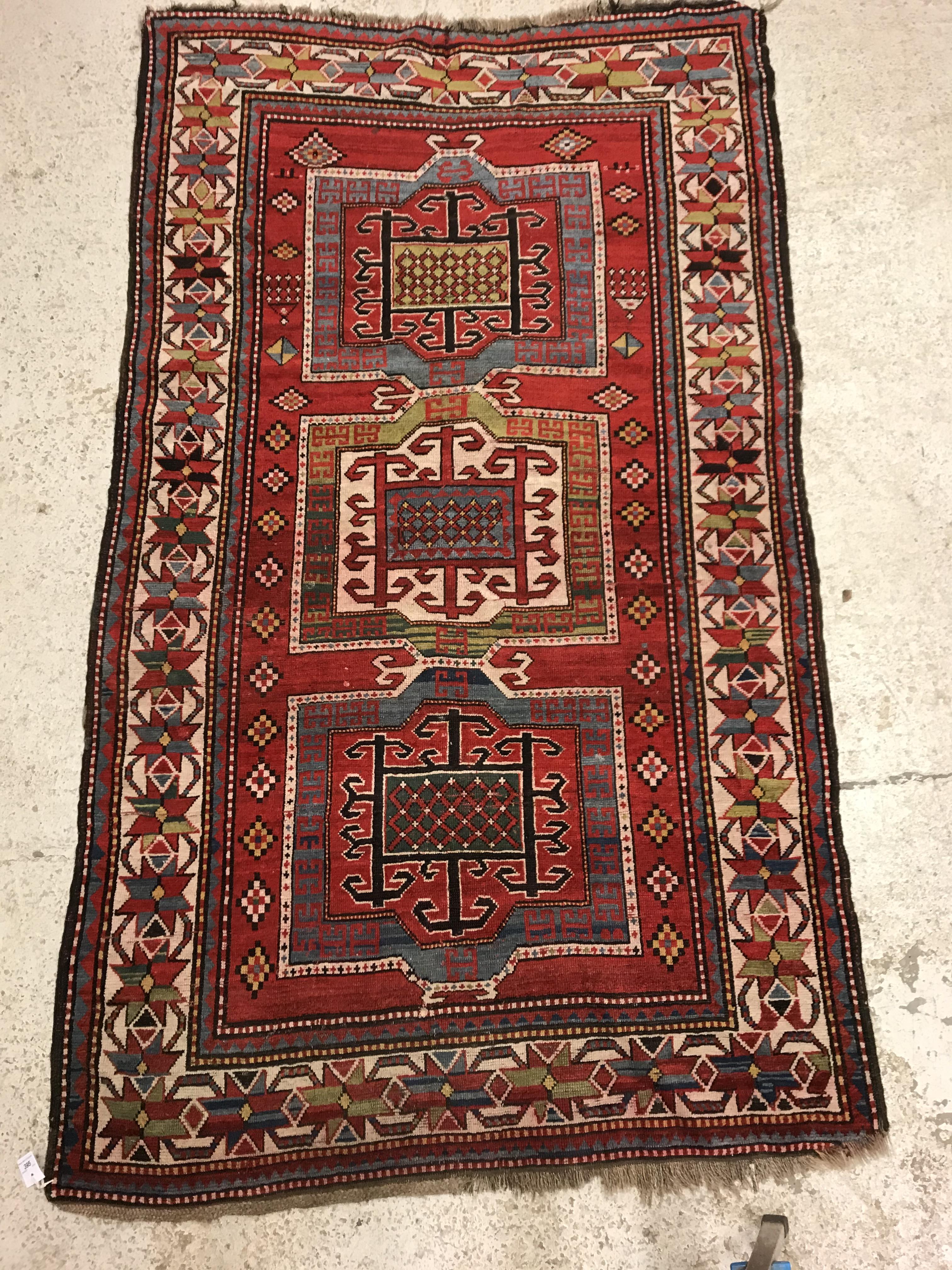 A Kasak runner, the central panel set with three repeating square medallions on a red ground