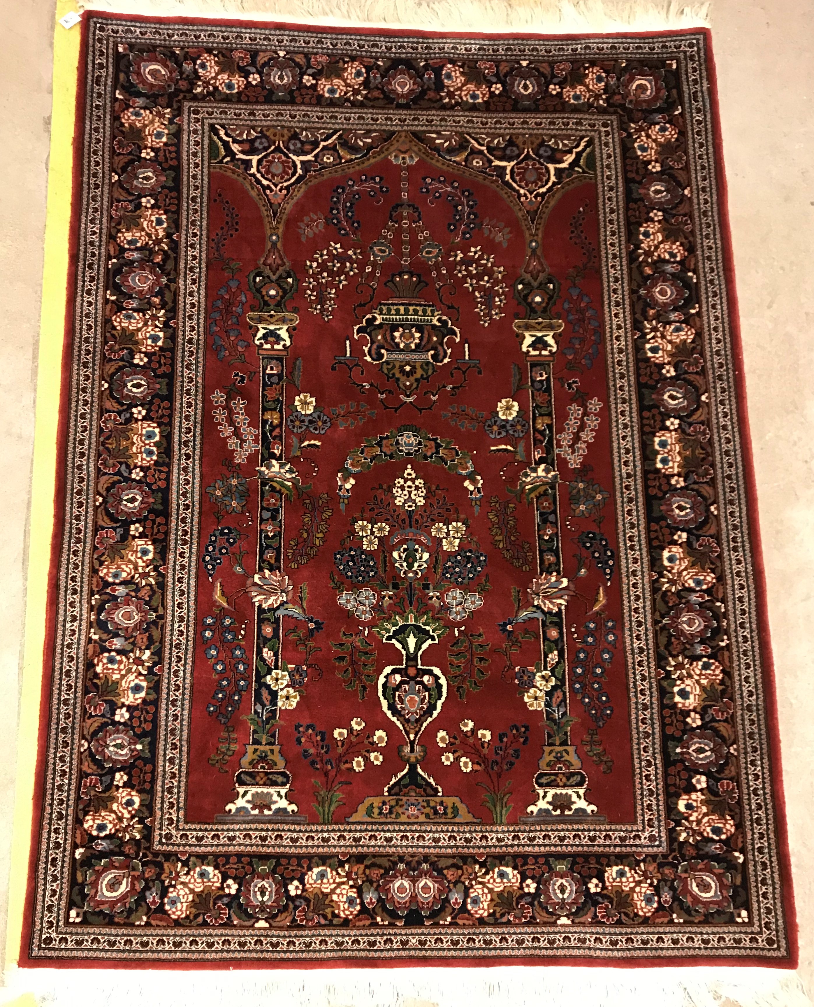 A Kashan prayer rug, the central panel set with Mirhab design with vase of flowers to base, on a red