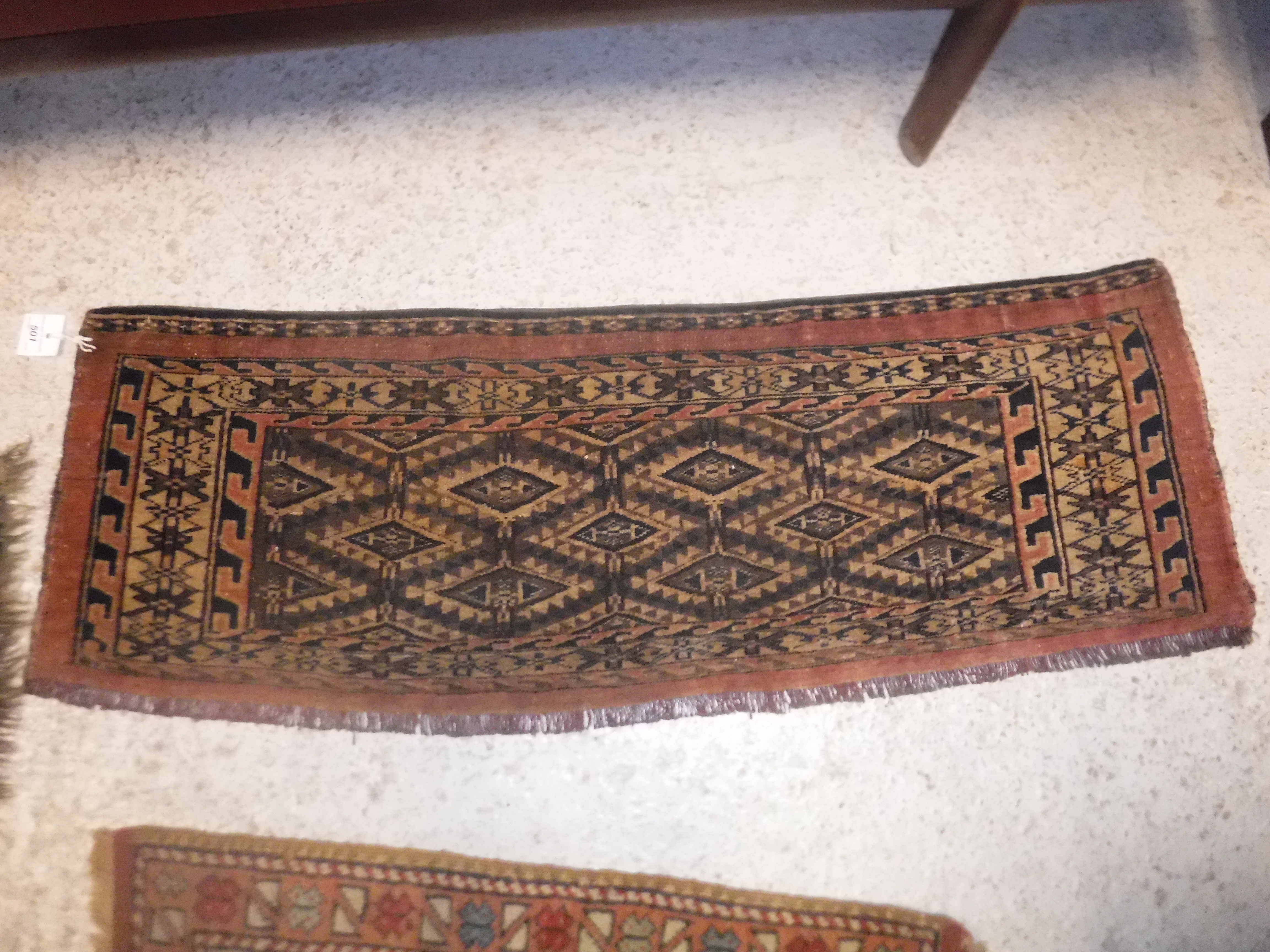 A Bokhara Torba rug, the central panel set with repeating lozenge medallions on a brown ground,