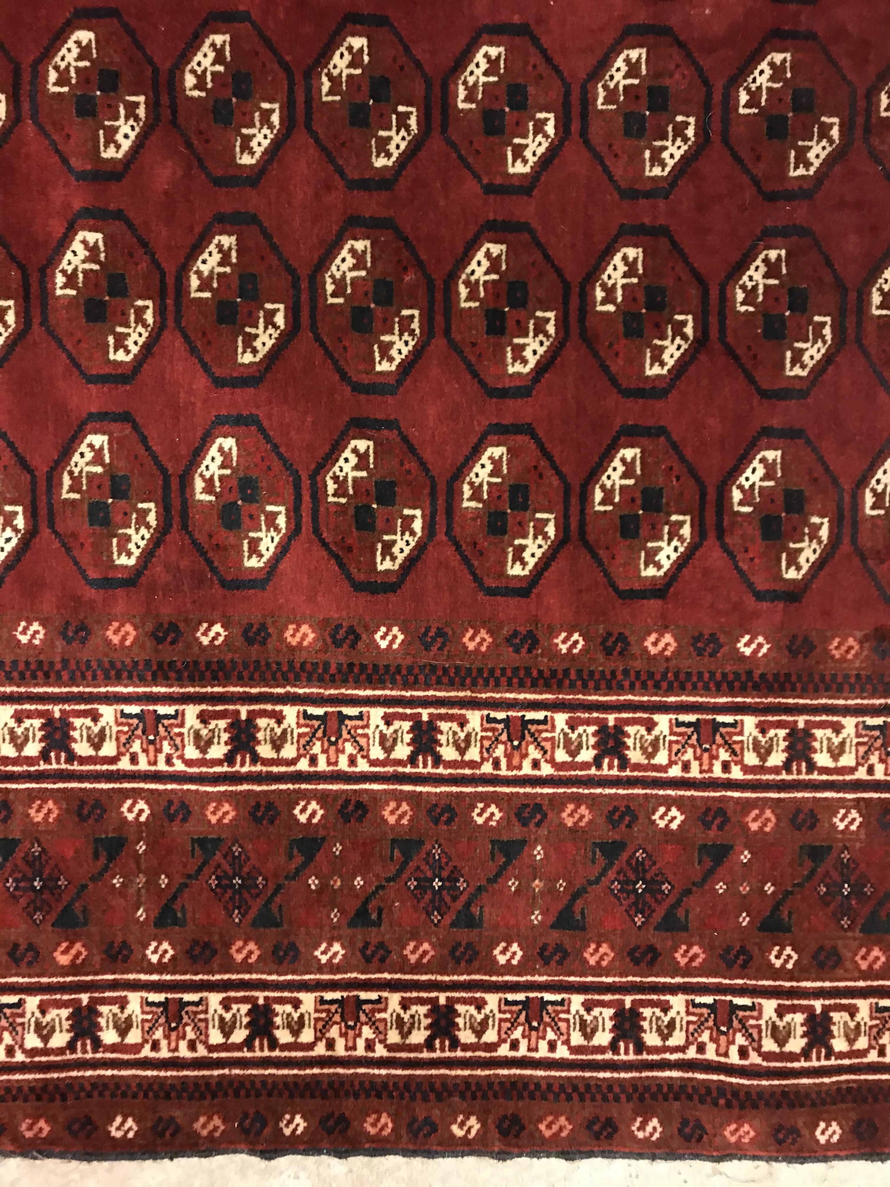 A Bokhara rug, the central panel set with repeating elephant foot style medallions on a dark red - Image 4 of 12