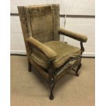 An oak framed wing back open arm chair in the early 18th Century manner, the arms on cabriole