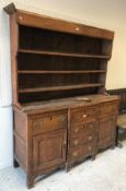 A late George III elm breakfront dresser, the three tier boarded plate rack over a single central
