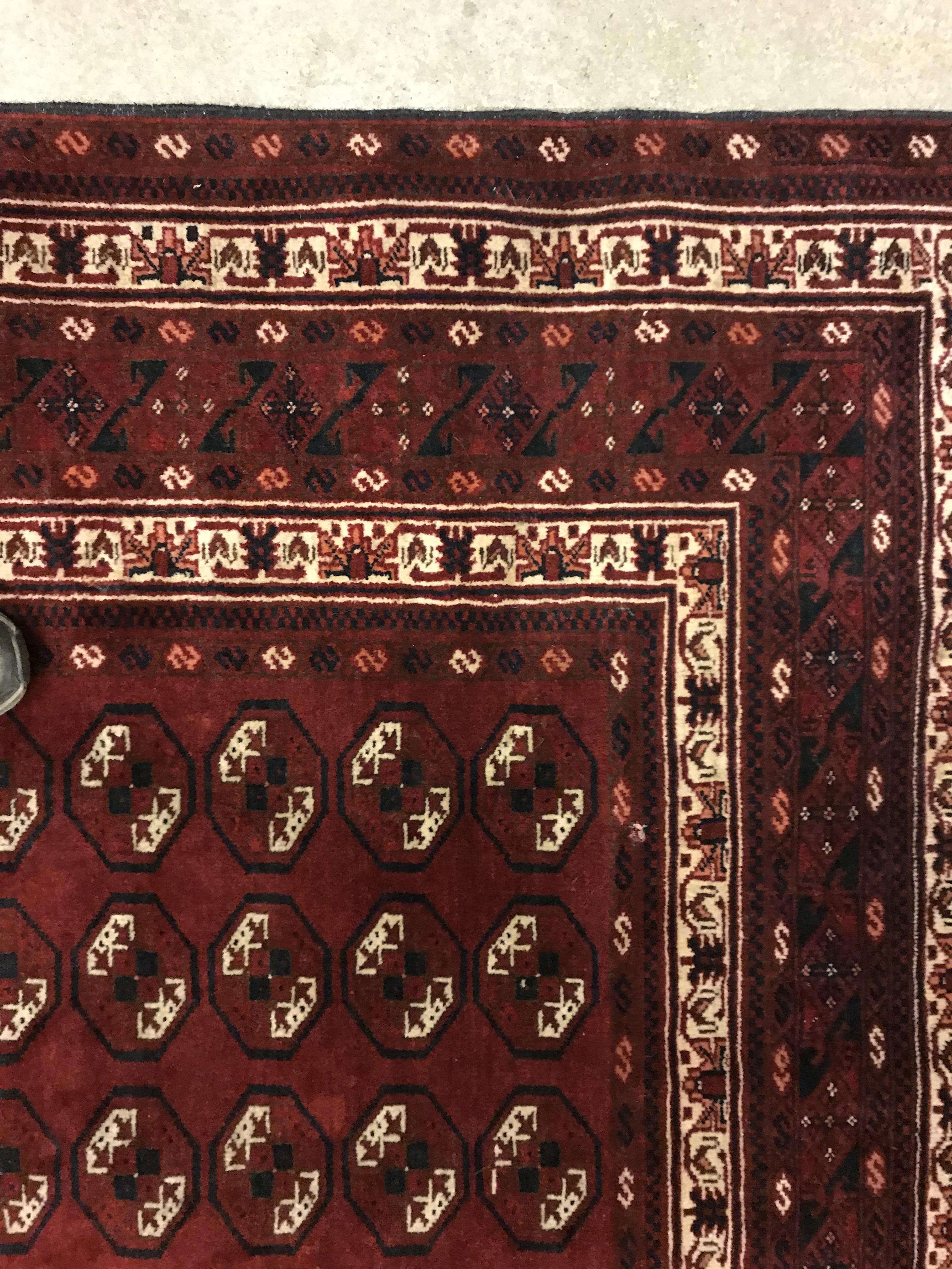 A Bokhara rug, the central panel set with repeating elephant foot style medallions on a dark red - Image 9 of 12