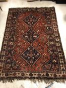 A Shiraz carpet, the central panel set with three joined diamond shaped medallions on a red and blue