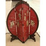 A 20th Century red lacquered and shibyama inlaid four fold screen of circular form, raised on carved