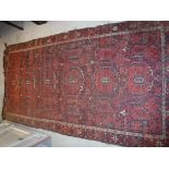 A Beshir carpet, the central panel set with repeating stylised floral motifs in red and black,