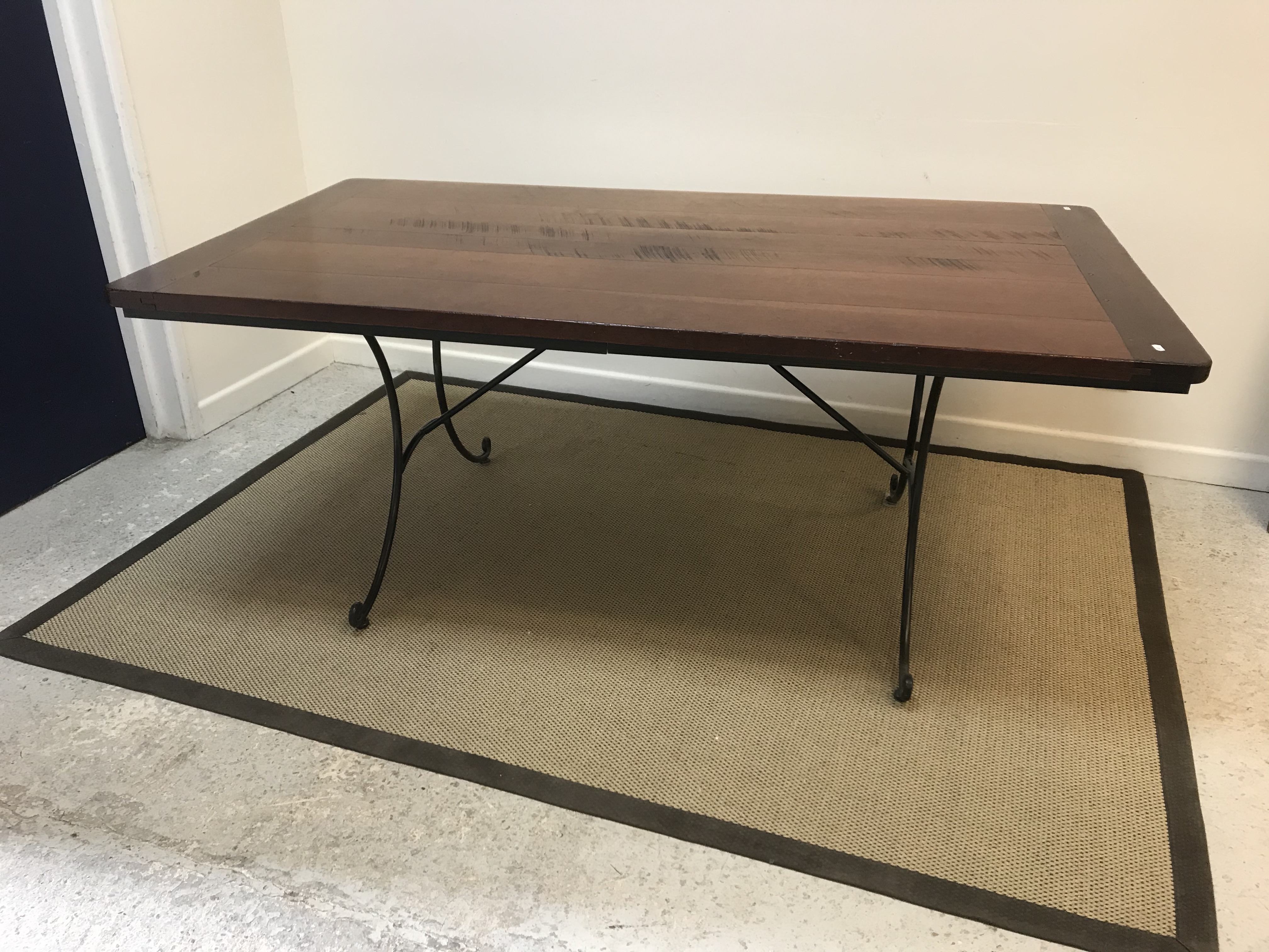 A modern cherry wood dining table, the plank top with cleated ends on a scrollwork wrought iron base