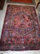 A Persian rug, the central panel set with a lozenge shaped medallion on a red floral decorated