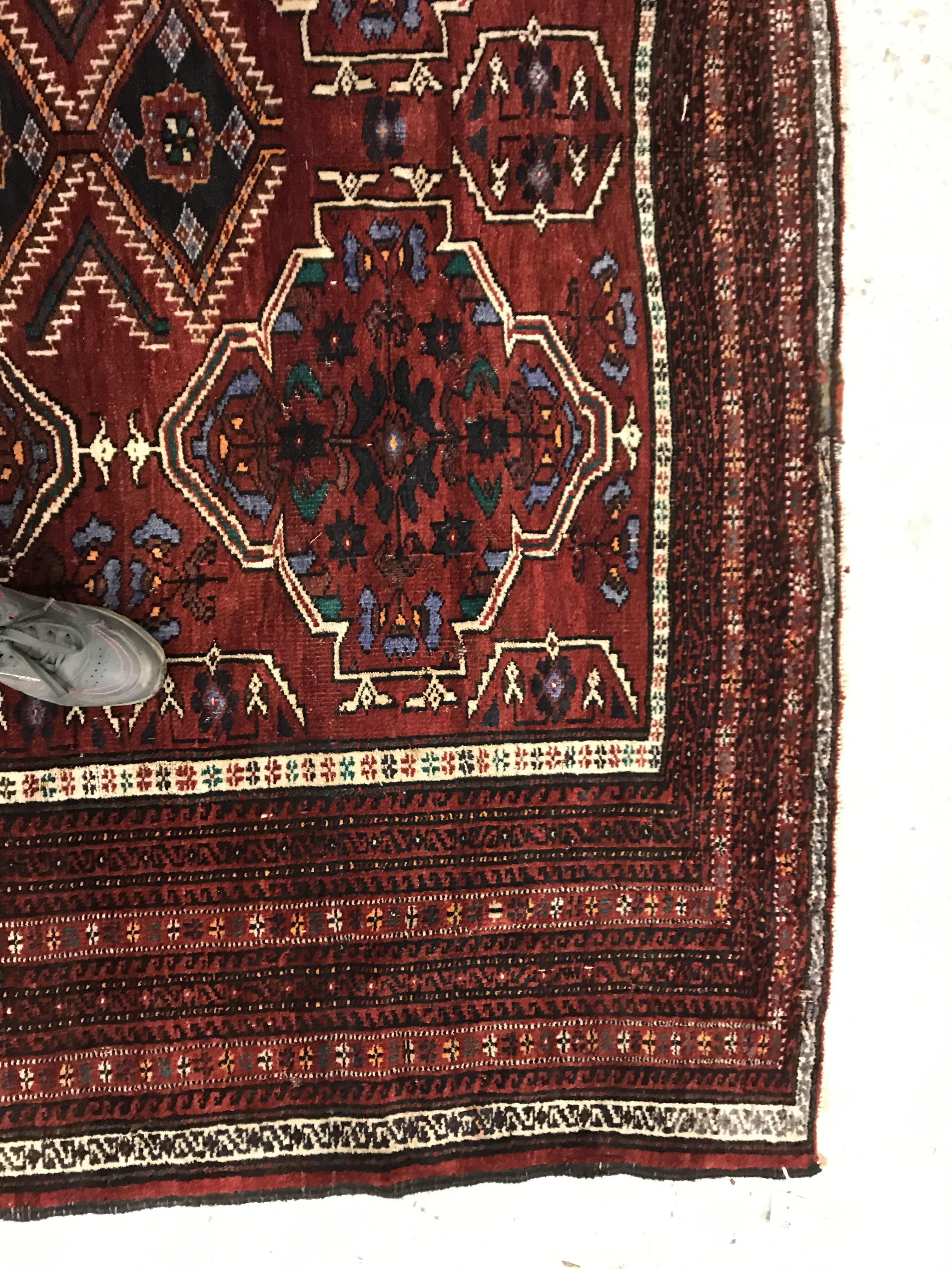 A Caucasian carpet, the central panel set with repeating medallion decoration on a blood red - Image 9 of 15