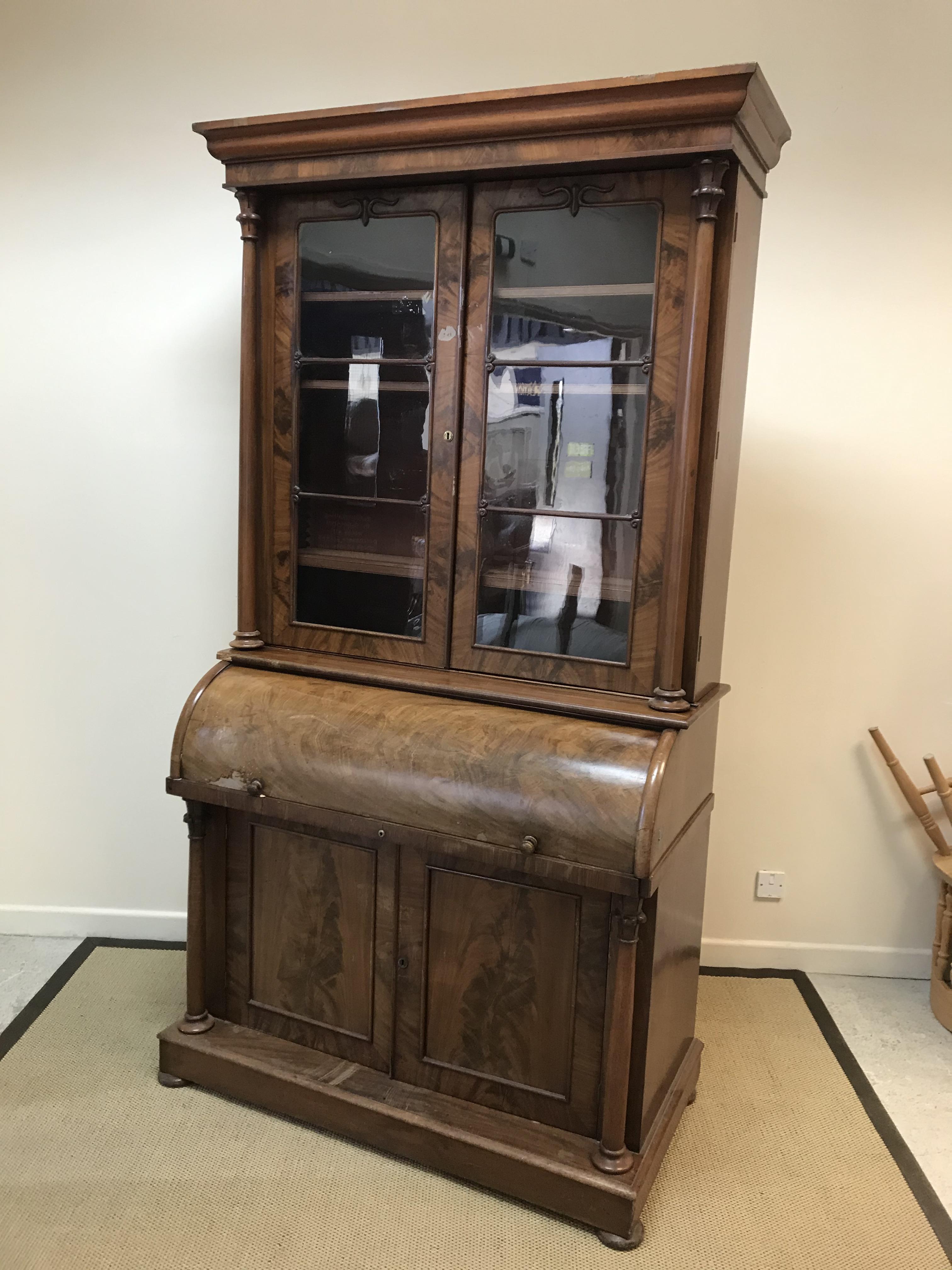 A Victorian mahogany cylinder bureau bookcase, the moulded cornice above two glazed and barred doors